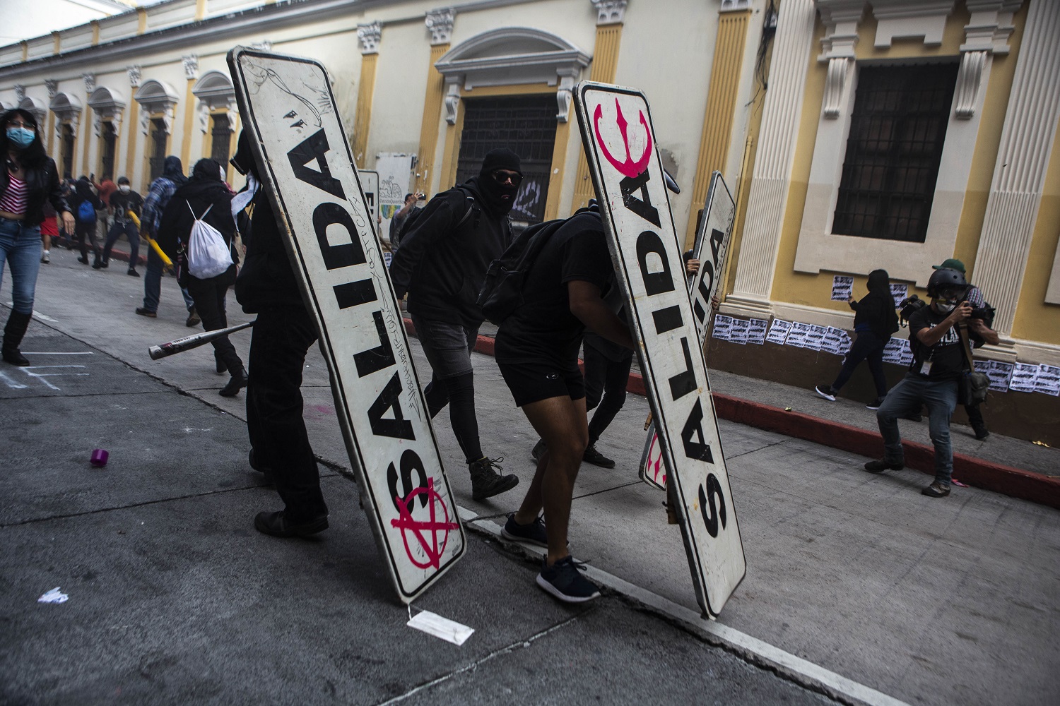Varios manifestantes se protegen contra los proyectiles de los antimotines con señales de tráfico el 21 de noviembre del 2020. | Foto: Oliver de Ros