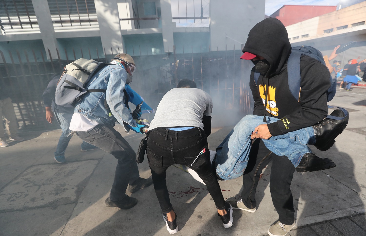 Varios manifestantes evacuan a Carlos tras ser alcanzado en el ojo por una bomba lacrimógena lanzada por los antimotines durante la protesta del 21 de noviembre del 2020. | Foto: Erick Avila / Prensa Libre